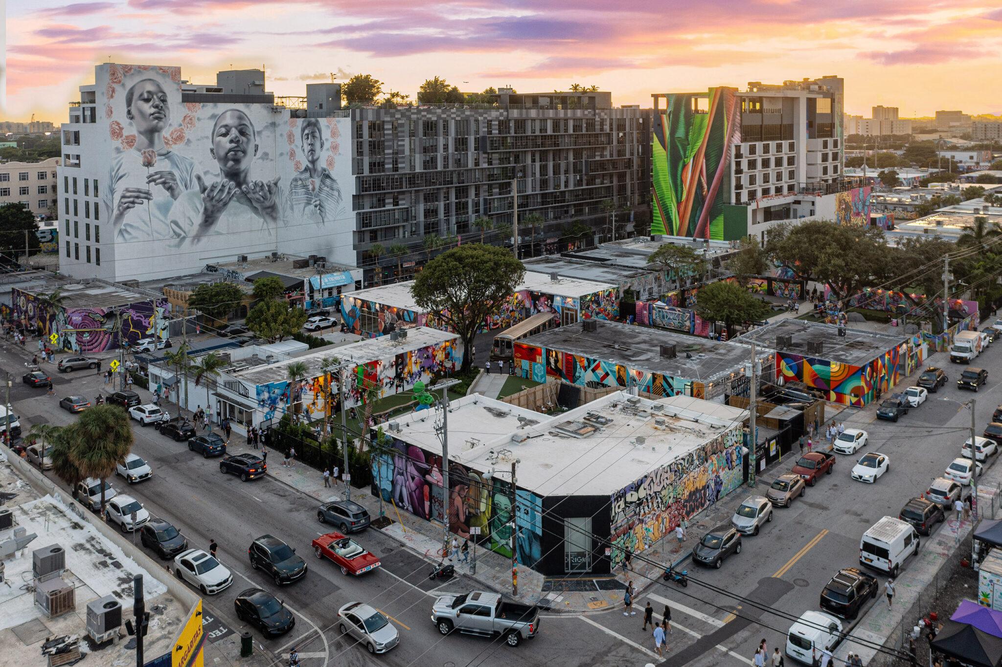 A colorful mural at Wynwood Walls in Miami with visitors walking past
